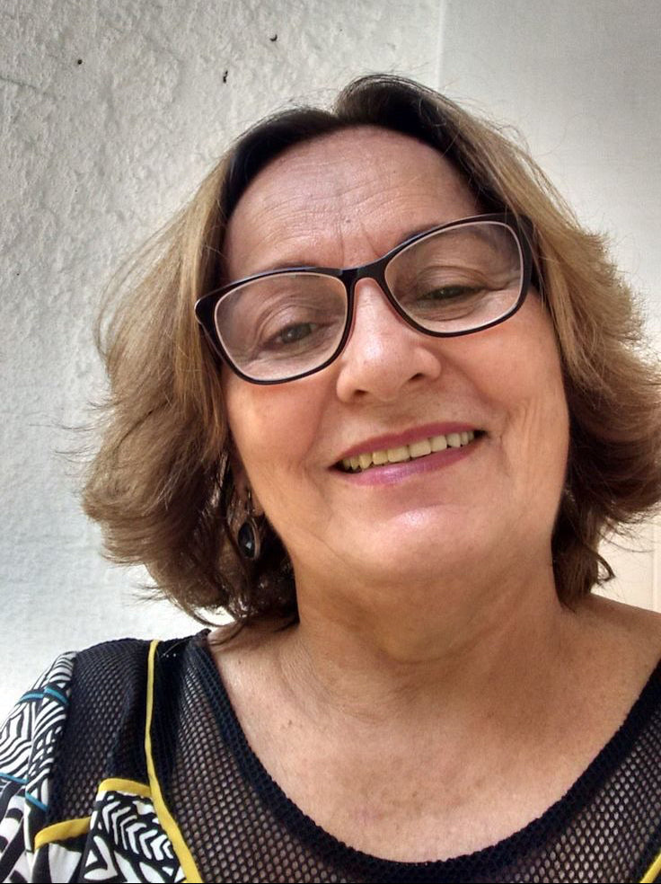 Woman with glasses smiling against a plain background